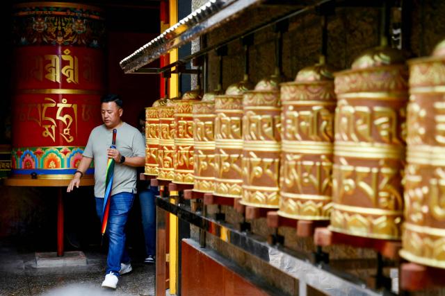 A man walks past prayer wheels at Nechung Monastery in McLeodganj on July 4, 2025. (Photo by Niharika Kulkarni / AFP)