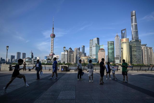 People visit The Bund promenade along the Huangpu River in Shanghai on July 4, 2025. (Photo by Hector RETAMAL / AFP)