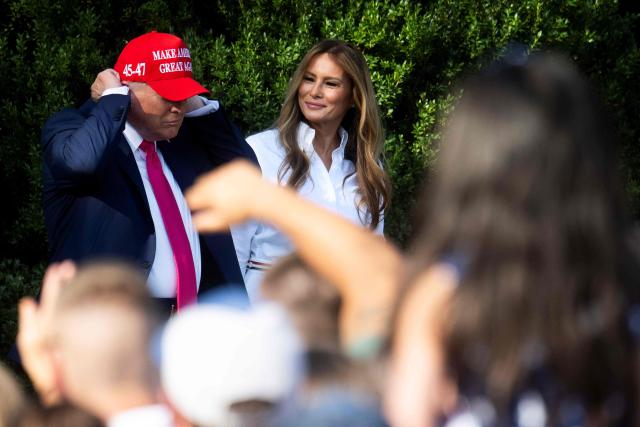 First Lady Melania Trump (C) smiles at US President Donald Trump as he dons his MAGA hat before greeting members of the military and their families during the Military Family Picnic on the South Lawn of the White House in Washington, DC, on July 4, 2025. (Photo by Jim WATSON / AFP)