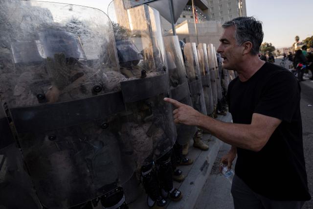 A demonstrator interacts with US marines and national guards standing in line protecting the entrance of the Metropolitan Detention Center as demonstrators gather in front of it following federal immigration operations, in Los Angeles, California on July 4, 2025. (Photo by Etienne LAURENT / AFP)