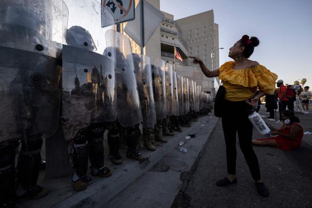 A demonstrator interacts with US marines and national guards standing in line protecting the entrance of the Metropolitan Detention Center as demonstrators gather in front of it following federal immigration operations, in Los Angeles, California on July 4, 2025. (Photo by Etienne LAURENT / AFP)