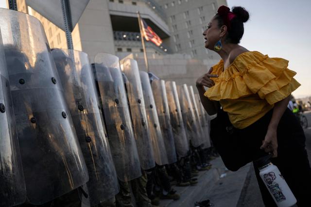 A demonstrator interacts with US marines and national guards standing in line protecting the entrance of the Metropolitan Detention Center as demonstrators gather in front of it following federal immigration operations, in Los Angeles, California on July 4, 2025. (Photo by Etienne LAURENT / AFP)
