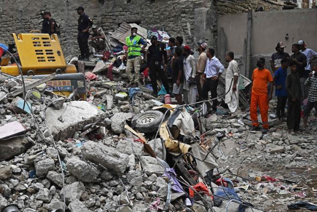 Rescue workers conduct a search operation amid the debris of a collapsed residential building in Karachi on July 5, 2025. Rescue teams pulled more bodies from the rubble of a five-storey building collapse in Pakistan overnight, taking the toll on July 5 to 14 as the recovery operation continued for a second day. (Photo by Rizwan TABASSUM / AFP)