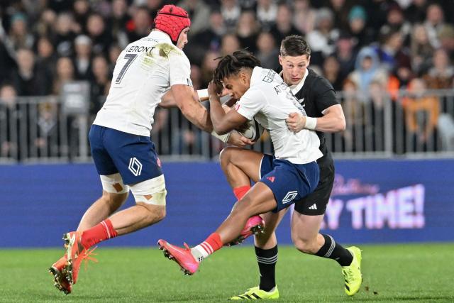 France's Theo Attissogbe (C) is tackled by New Zealand's Cam Roigard (R) during the first international rugby Test match between New Zealand and France at Forsyth Barr Stadium in Dunedin on July 5, 2025. (Photo by Sanka Vidanagama / AFP)