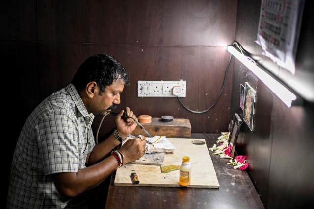 A goldsmith heats up gold to repair it at a workshop in Chennai on July 5, 2025. New Delhi and Washington have been locked in multiple rounds of talks, with hopes for an interim pact to avert the 26 percent "reciprocal" tolls meted out to India. (Photo by R. Satish BABU / AFP)