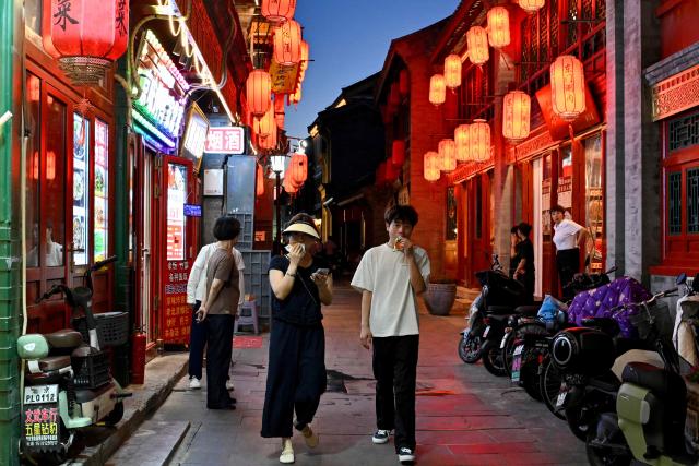 People walk along Qianmen promenade in Beijing on July 5, 2025. (Photo by Adek BERRY / AFP)