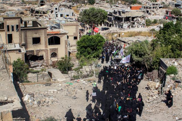 Shiite Muslim worshippers walk past the rubble of buildings destroyed by previous Israeli strikes during a mourning procession in Lebanon's southern village of Kfarkila near the border with Israel on July 5, 2025, which coincides with the ninth day of the Islamic month of Muharram in the lead-up to Ashura, a 10-day period commemorating the seventh century killing of Prophet Mohammed's grandson Imam Hussein. (Photo by Rabih DAHER / AFP)