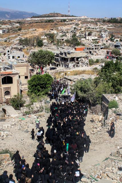 Shiite Muslim worshippers walk past the rubble of buildings destroyed by previous Israeli strikes during a mourning procession in Lebanon's southern village of Kfarkila near the border with Israel on July 5, 2025, which coincides with the ninth day of the Islamic month of Muharram in the lead-up to Ashura, a 10-day period commemorating the seventh century killing of Prophet Mohammed's grandson Imam Hussein. (Photo by Rabih DAHER / AFP)