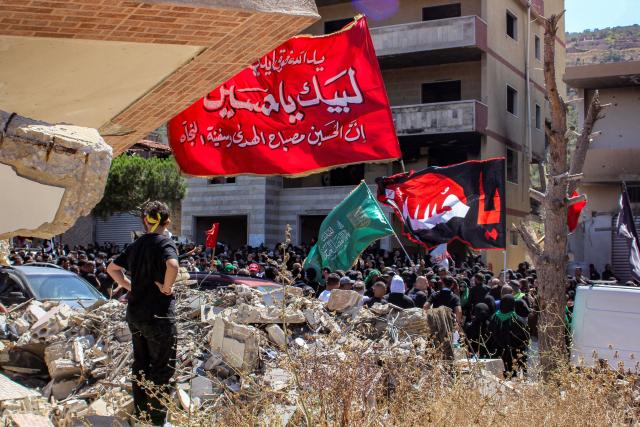 Shiite Muslim worshippers walk past the rubble of buildings destroyed by previous Israeli strikes during a mourning procession in Lebanon's southern village of Kfarkila near the border with Israel on July 5, 2025, which coincides with the ninth day of the Islamic month of Muharram in the lead-up to Ashura, a 10-day period commemorating the seventh century killing of Prophet Mohammed's grandson Imam Hussein. (Photo by Rabih DAHER / AFP)