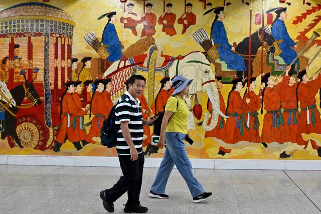 People walk past a mural at the Wangfujing subway station in Beijing on July 5, 2025. (Photo by Adek BERRY / AFP)