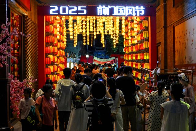 People walk along Qianmen promenade in Beijing on July 5, 2025. (Photo by Adek BERRY / AFP)