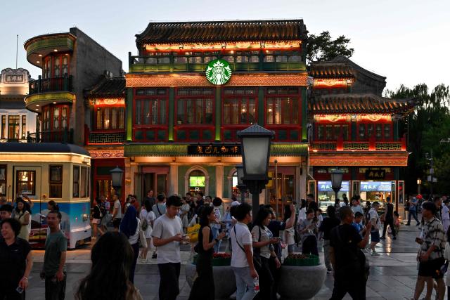 People walk along Qianmen promenade in Beijing on July 5, 2025. (Photo by Adek BERRY / AFP)