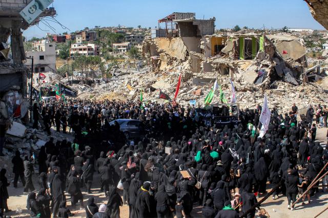 Shiite Muslim worshippers walk past the rubble of buildings destroyed by previous Israeli strikes during a mourning procession in Lebanon's southern village of Kfarkila near the border with Israel on July 5, 2025, which coincides with the ninth day of the Islamic month of Muharram in the lead-up to Ashura, a 10-day period commemorating the seventh century killing of Prophet Mohammed's grandson Imam Hussein. (Photo by Rabih DAHER / AFP)