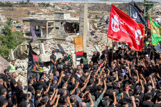 Shiite Muslim worshippers walk past the rubble of buildings destroyed by previous Israeli strikes during a mourning procession in Lebanon's southern village of Kfarkila near the border with Israel on July 5, 2025, which coincides with the ninth day of the Islamic month of Muharram in the lead-up to Ashura, a 10-day period commemorating the seventh century killing of Prophet Mohammed's grandson Imam Hussein. (Photo by Rabih DAHER / AFP)