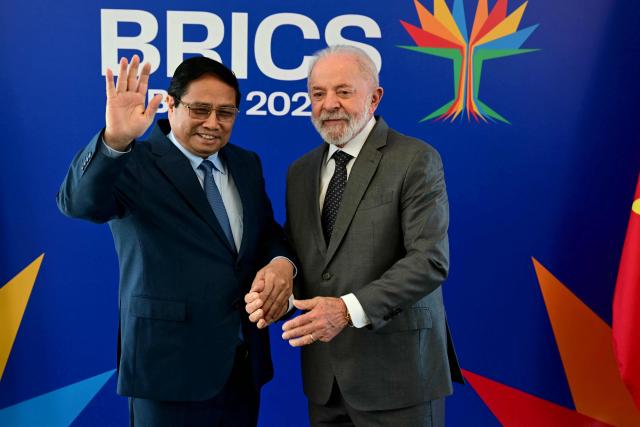 Vietnam's Prime Minister Pham Minh Chinh (L) waves next to Brazil's President Luiz Inacio Lula da Silva before a bilateral meeting ahead of the BRICS summit in Rio de Janeiro, Brazil, on July 5, 2025. BRICS leaders meeting in Rio de Janeiro from Sunday are expected to decry Donald Trump's hardline trade policies, but are struggling to bridge divides over crises roiling the Middle East. (Photo by Pablo PORCIUNCULA / AFP)