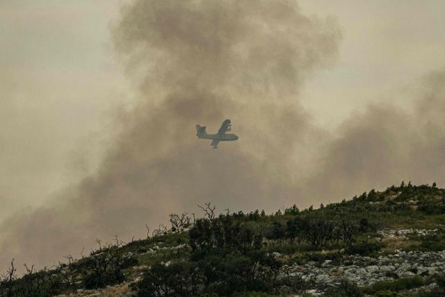 This photograph shows a Canadair aerial firefighting aircaft throught the smoke-filled  during a wildfire on the side of the A6 motorway near Moux, southwest France, on July 5, 2025. (Photo by IDRISS BIGOU-GILLES / AFP)