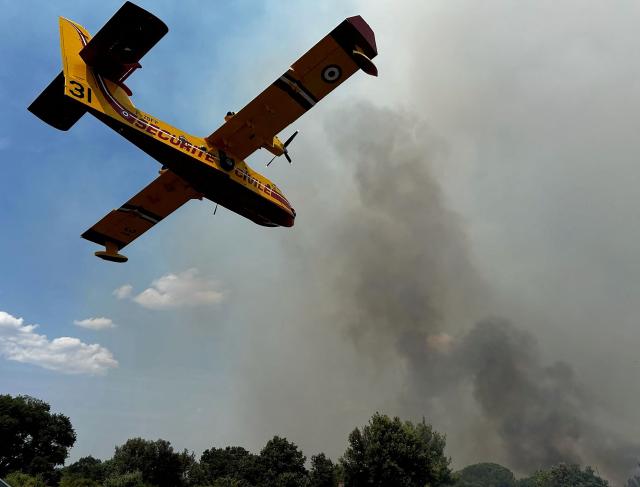 A Canadair aerial firefighting aircaft flies over a wildfire on the side of the A6 motorway near Moux, south-western France, on July 5, 2025. (Photo by Laurent NOE / VINCI AUTOROUTES / AFP)