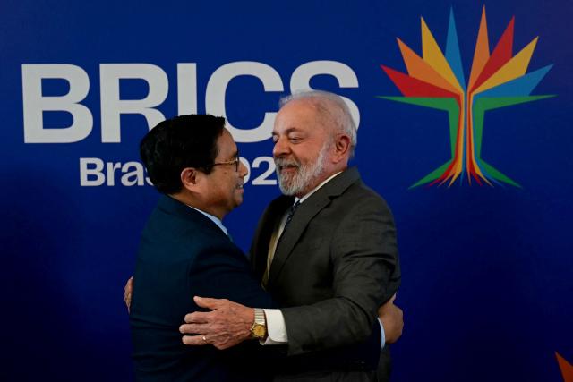 Vietnam's Prime Minister Pham Minh Chinh (L) and Brazil's President Luiz Inacio Lula da Silva greet each other as they celebrate the completion of the first export of Brazilian beef to Vietnam and the first export of Vietnamese tilapia to Brazil after a bilateral meeting ahead of the BRICS summit in Rio de Janeiro, Brazil, on July 5, 2025. BRICS leaders meeting in Rio de Janeiro from Sunday are expected to decry Donald Trump's hardline trade policies, but are struggling to bridge divides over crises roiling the Middle East. (Photo by Pablo PORCIUNCULA / AFP)
