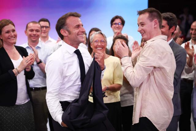 France's President Emmanuel removes his blazer next to President of "Les Jeunes avec Macron" Ambroise Mejean as France's Minister of Education, Higher Education and Research Elisabeth Borne (C) looks on during a rally marking the 10th anniversary of "Les Jeunes avec Macron" (Youth with Macron), the youth movement of the Renaissance party, at the Cirque d'Hiver in Paris on July 5, 2025. (Photo by Sebastien DUPUY / AFP)