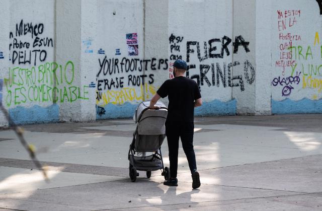 A man walks in front of a wall of Mexico Park with graffiti a day after a march against gentrification and the increasing presence of US citizens in the La Condesa neighbourhood of Mexico City on July 5, 2025. Shouting "gringos out!" and waving banners and vandalizing various businesses, hundreds of people demonstrated this Friday in Mexico City against the gentrification of various neighborhoods due to the arrival of foreigners. (Photo by Yuri CORTEZ / AFP)