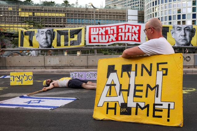 A demonstrator poses with a placard during an anti-government protest calling for action to secure the release of Israeli hostages held captive in the Gaza Strip by Palestinian militants since the 2023 October 7 attacks, outside the Israeli Defence Ministry headquarters in Tel Aviv on July 5, 2025. (Photo by Jack GUEZ / AFP)