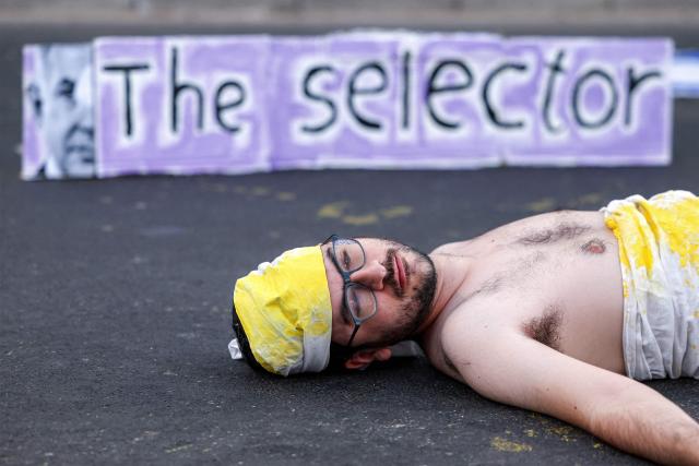 A demonstrator lies on the ground while depicting an Israeli hostage during an anti-government protest calling for action to secure the release of Israeli hostages held captive in the Gaza Strip by Palestinian militants since the 2023 October 7 attacks, outside the Israeli Defence Ministry headquarters in Tel Aviv on July 5, 2025. (Photo by Jack GUEZ / AFP)