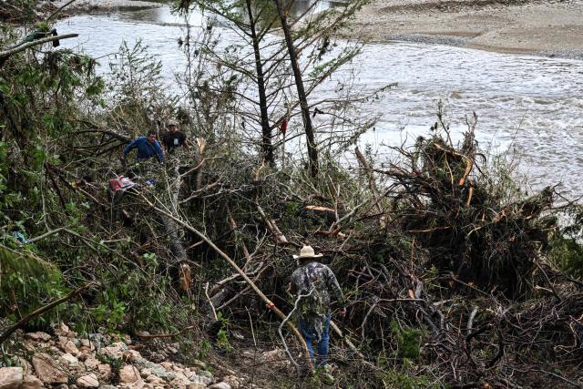 Volunteers search for missing people near Camp Mystic, the site of where at least 20 girls went missing after flash flooding in Hunt, Texas, on July 5, 2025. Rescuers were on Saturday searching for more than 20 girls missing from a riverside summer camp in the US state of Texas, after torrential rains caused devastating flooding that killed at least 27 people -- with more rain on the way. "So far, we've evacuated over 850 uninjured people, eight injured people and have recovered 27 deceased fatalities at this time. Of these 27, 18 are adults, nine are children," said Kerr Country Sheriff Larry Leitha on July 5. (Photo by RONALDO SCHEMIDT / AFP)