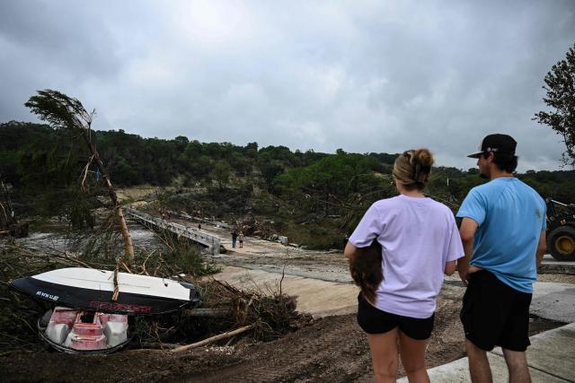 People look on as law enforcement and volunteers continue to search for missing people near Camp Mystic, the site of where at least 20 girls went missing after flash flooding in Hunt, Texas, on July 5, 2025. Rescuers were on Saturday searching for more than 20 girls missing from a riverside summer camp in the US state of Texas, after torrential rains caused devastating flooding that killed at least 27 people -- with more rain on the way. "So far, we've evacuated over 850 uninjured people, eight injured people and have recovered 27 deceased fatalities at this time. Of these 27, 18 are adults, nine are children," said Kerr Country Sheriff Larry Leitha on July 5. (Photo by RONALDO SCHEMIDT / AFP)