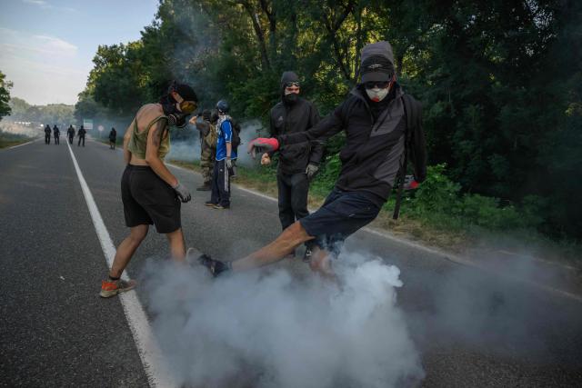 Protesters try to kick back a teargas fired by police during a demonstration dubbed "Turbo-Teuf" against the A69 motorway project, in Morens-Scopont, southern France, on July 5, 2025. Environmental groups are holding a protest in the Tarn deparment against the construction of the Toulouse-Castres A69 motorway, despite the gathering's ban by authorities. (Photo by Ed JONES / AFP)