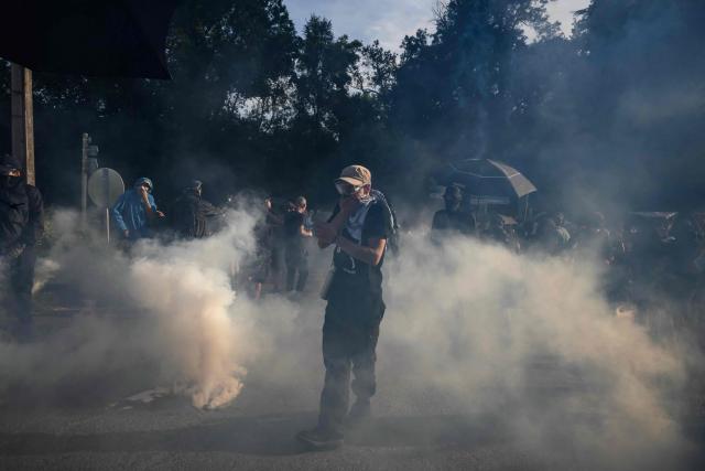 A protester reacts to teargas as they clash with police during a demonstration dubbed "Turbo-Teuf" against the A69 motorway project, in Morens-Scopont, southern France, on July 5, 2025. Environmental groups are holding a protest in the Tarn deparment against the construction of the Toulouse-Castres A69 motorway, despite the gathering's ban by authorities. (Photo by Ed JONES / AFP)