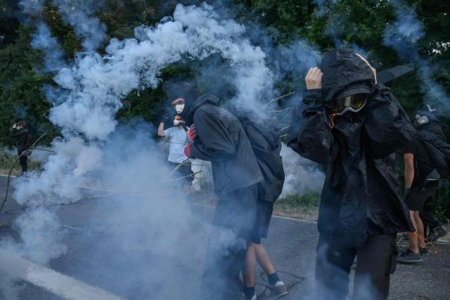TOPSHOT - Protesters react to teargas as they clash with police during a demonstration dubbed "Turbo-Teuf" against the A69 motorway project, in Morens-Scopont, southern France, on July 5, 2025. Environmental groups are holding a protest in the Tarn deparment against the construction of the Toulouse-Castres A69 motorway, despite the gathering's ban by authorities. (Photo by Ed JONES / AFP)