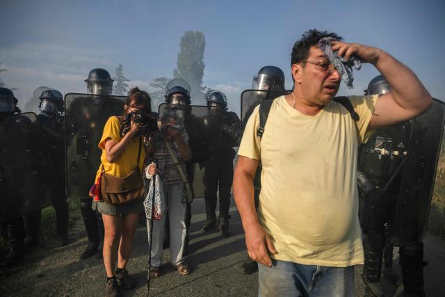 Protesters react to teargas as they clash with police during a demonstration dubbed "Turbo-Teuf" against the A69 motorway project, in Morens-Scopont, southern France, on July 5, 2025. Environmental groups are holding a protest in the Tarn deparment against the construction of the Toulouse-Castres A69 motorway, despite the gathering's ban by authorities. (Photo by Ed JONES / AFP)