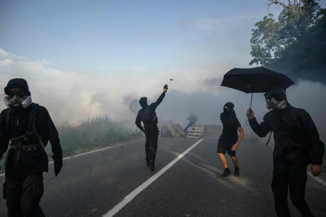 TOPSHOT - A protester throws a stone as they clash with police during a demonstration dubbed "Turbo-Teuf" against the A69 motorway project, in Morens-Scopont, southern France, on July 5, 2025. Environmental groups are holding a protest in the Tarn deparment against the construction of the Toulouse-Castres A69 motorway, despite the gathering's ban by authorities. (Photo by Ed JONES / AFP)