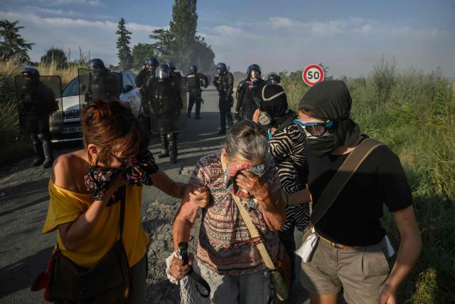 Protesters react to teargas as they clash with police during a demonstration dubbed "Turbo-Teuf" against the A69 motorway project, in Morens-Scopont, southern France, on July 5, 2025. Environmental groups are holding a protest in the Tarn deparment against the construction of the Toulouse-Castres A69 motorway, despite the gathering's ban by authorities. (Photo by Ed JONES / AFP)