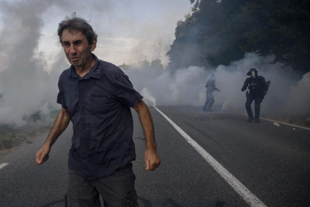 A protester reacts to teargas as they clash with police during a demonstration dubbed "Turbo-Teuf" against the A69 motorway project, in Morens-Scopont, southern France, on July 5, 2025. Environmental groups are holding a protest in the Tarn deparment against the construction of the Toulouse-Castres A69 motorway, despite the gathering's ban by authorities. (Photo by Ed JONES / AFP)
