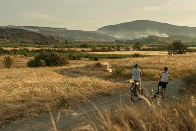 Youths on bicycles watch the smoke rising during a wildfire near Fontcouverte, southwest France, on July 5, 2025. (Photo by IDRISS BIGOU-GILLES / AFP)