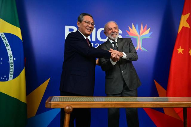 Brazil's President Luiz Inacio Lula da Silva (R) and China's Premier Li Qiang pose for a picture after a bilateral meeting ahead of the BRICS summit in Rio de Janeiro, Brazil, on July 5, 2025. BRICS leaders meeting in Rio de Janeiro from Sunday are expected to decry Donald Trump's hardline trade policies, but are struggling to bridge divides over crises roiling the Middle East. (Photo by Pablo PORCIUNCULA / AFP)