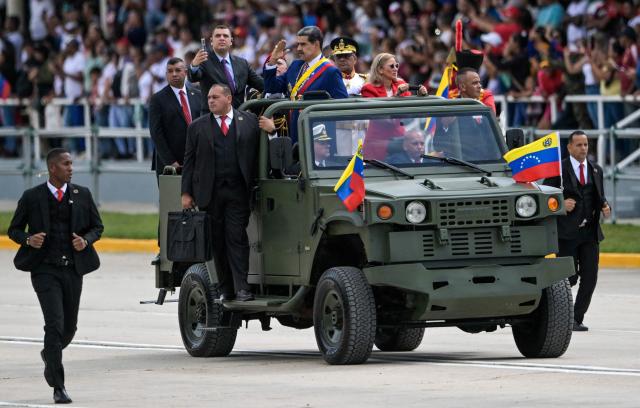 Venezuela's President Nicolas Maduro and First Lady Cilia Flores parade in a military vehicle during celebrations for the Independence Day, in Caracas on July 5, 2025. (Photo by Juan BARRETO / AFP)