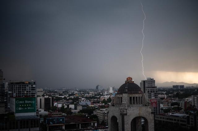 Lightning strikes a building behind the iconic Monument to the Revolution during a thunderstorm in Mexico City on July 5, 2025. (Photo by Yuri CORTEZ / AFP)