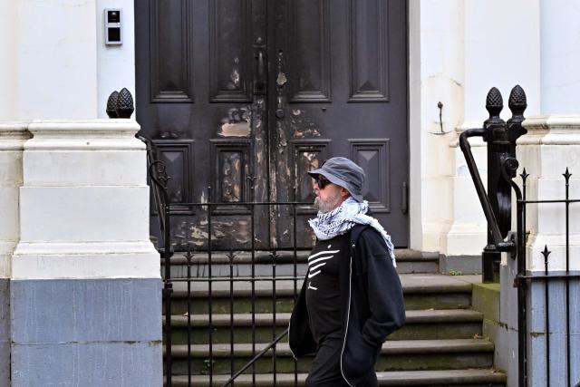 A man walks past the burnt front entrance of the East Melbourne Synagogue in Melbourne on July 6, 2025. A man suspected of setting fire to an Australian synagogue as worshippers ate dinner inside has been arrested and charged, police said on July 6. (Photo by William WEST / AFP)