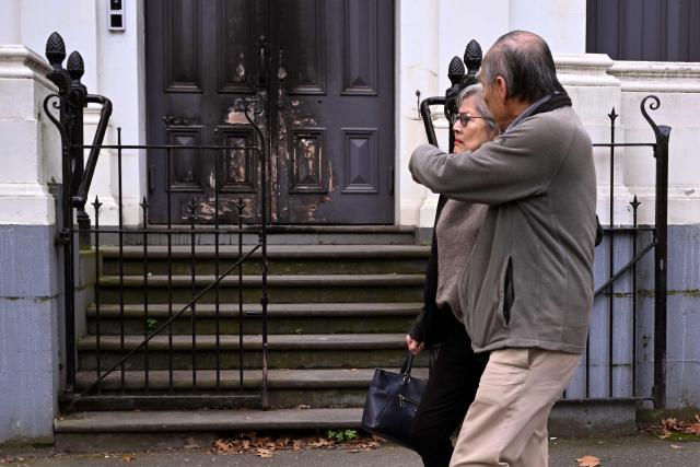 People pass the burnt front entrance of the East Melbourne Synagogue in Melbourne on July 6, 2025. A man suspected of setting fire to an Australian synagogue as worshippers ate dinner inside has been arrested and charged, police said on July 6. (Photo by William WEST / AFP)