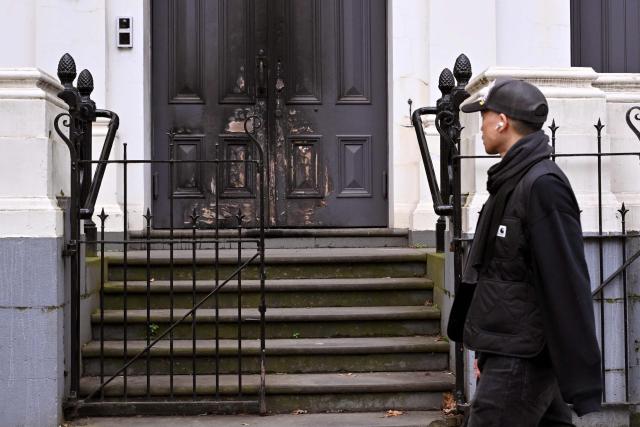 A man walks past the burnt front entrance of the East Melbourne Synagogue in Melbourne on July 6, 2025. A man suspected of setting fire to an Australian synagogue as worshippers ate dinner inside has been arrested and charged, police said on July 6. (Photo by William WEST / AFP)
