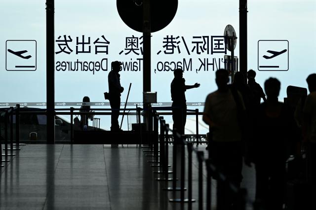 A security guard guides passengers at Beijing International airport on July 6, 2025. (Photo by WANG Zhao / AFP)