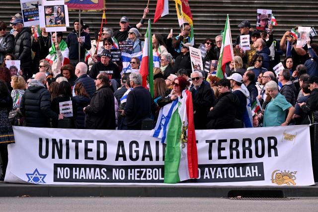 People listen to speeches at a rally in Melbourne on July 6, 2025, after the front door of a synagogue was set ablaze on July 4. A man suspected of setting fire to an Australian synagogue as worshippers ate dinner inside has been arrested and charged, police said on July 6. (Photo by William WEST / AFP)