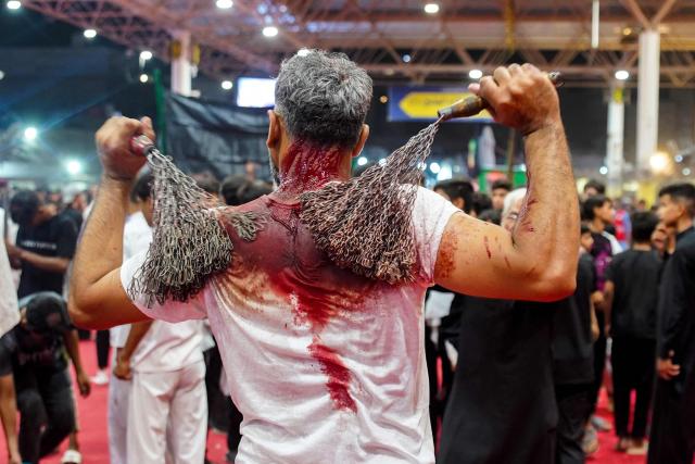 A Shiite Muslim man flagellates himself with metal chains during Tatbir, a mourning ritual marking Ashura, a 10-day period commemorating the seventh century killing of Prophet Mohammed's grandson Imam Hussein, in Iraq's central holy city of Najaf on July 5, 2025. (Photo by Qassem al-KAABI / AFP)