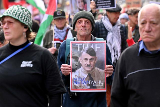A demonstrator holds a placard depicting Israeli Prime Minister Benjamin Netanyahu as Adolf Hitler during a pro-Palestinian march through the streets of Melbourne on July 6, 2025, amid the ongoing conflict between Israel and the Palestinian Hamas militant group. (Photo by William WEST / AFP)