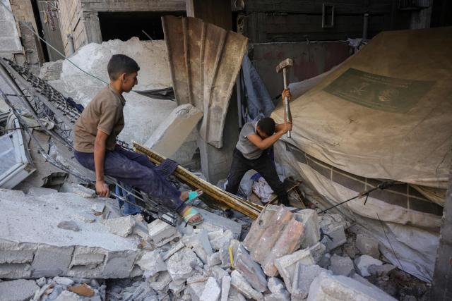 A Palestinian child looks on as a man searches for survivors in the rubble of a building in the Sheikh Radwan neighbourhood in Gaza City, in the central Gaza Strip that was targeted in an Israeli strike on July 6, 2025. An Israeli delegation was expected in Doha on July 6 for talks on a Gaza truce and hostage release deal, after Palestinian group Hamas said it was ready to start negotiations "immediately". (Photo by Bashar TALEB / AFP)