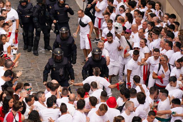 Police control the crowd as revellers gather to celebrate during the "Chupinazo" (rocket launch) marking the official start of the San Fermin Festival in Plaza Consistorial outside the Town Hall of Pamplona in northern Spain on July 6, 2025. Thousands of people every year attend the week-long festival and its famous 'encierros' (bull runs) in which six bulls are released at 8:00 a.m. evey day starting July 7, to run from their corral to the bullring through the narrow streets of the old town over an 850 meters (yard) course while runners ahead of them try to stay close to the bulls without falling over or being gored. (Photo by CESAR MANSO / AFP)