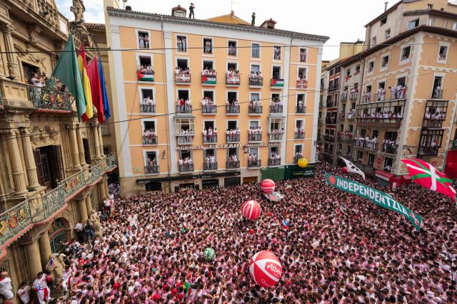 Revellers gather to celebrate during the "Chupinazo" (rocket launch) marking the official start of the San Fermin Festival in Plaza Consistorial outside the Town Hall of Pamplona in northern Spain on July 6, 2025. Thousands of people every year attend the week-long festival and its famous 'encierros' (bull runs) in which six bulls are released at 8:00 a.m. evey day starting July 7, to run from their corral to the bullring through the narrow streets of the old town over an 850 meters (yard) course while runners ahead of them try to stay close to the bulls without falling over or being gored. (Photo by Cesar Manso / AFP)
