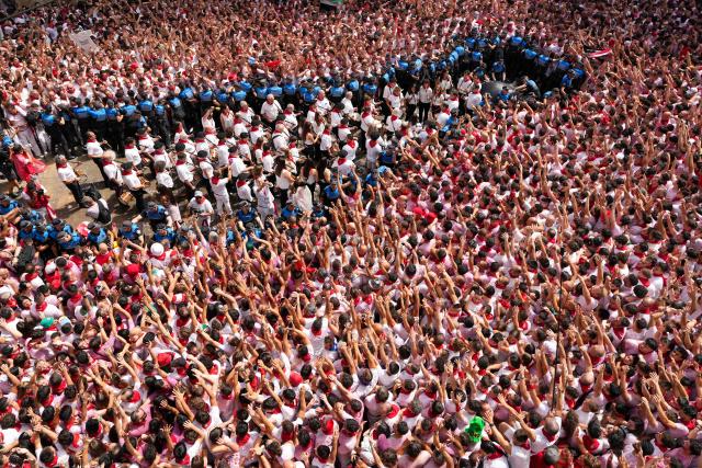 The "Pamplonesa" municipal music band performs during the "Chupinazo" (rocket launch) marking the official start of the San Fermin Festival in Plaza Consistorial outside the Town Hall of Pamplona in northern Spain on July 6, 2025. Thousands of people every year attend the week-long festival and its famous 'encierros' (bull runs) in which six bulls are released at 8:00 a.m. evey day starting July 7, to run from their corral to the bullring through the narrow streets of the old town over an 850 meters (yard) course while runners ahead of them try to stay close to the bulls without falling over or being gored. (Photo by Cesar Manso / AFP)